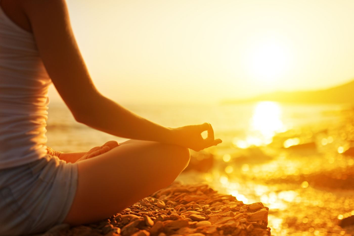 A woman doing yoga on a beach at sunrise